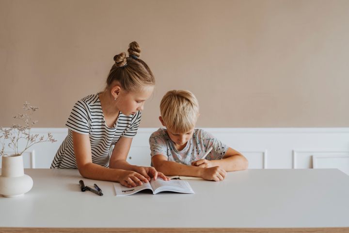 Two children reading a book together at a table